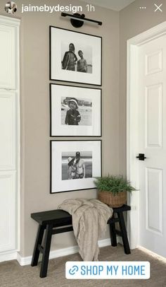 a room with pictures hanging on the wall and a small bench in front of it