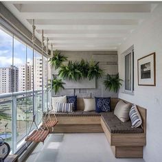 a couch sitting on top of a wooden bench next to a window filled with plants