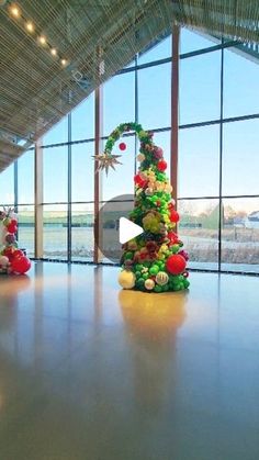 a christmas tree made out of fruits and vegetables in front of large windows at an airport