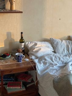 a bottle of wine is sitting on a table next to a bed