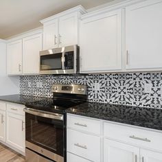 a kitchen with white cabinets and black counter tops