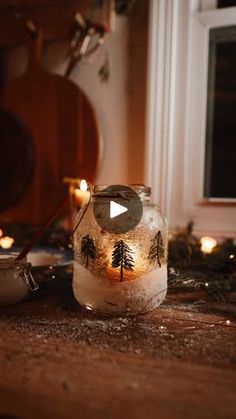 a glass jar filled with liquid sitting on top of a wooden table next to candles