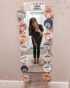 a woman standing in front of a mirror holding a cell phone and taking a selfie