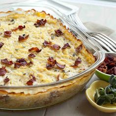 a casserole dish with bacon and cheese in it next to two small bowls