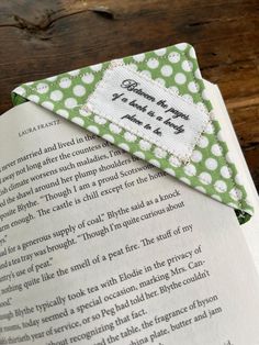 an open book with a green and white polka dot ribbon