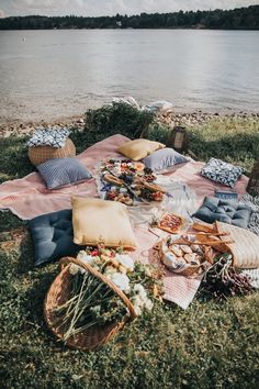 a picnic is set up on the bank of a lake with food and drinks laid out