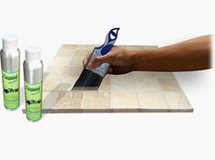 a person using a tile grouter on a counter top with three spray bottles next to it