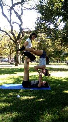 two people doing yoga in the park on their stomachs and arms, with one person upside down