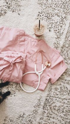 a cat laying on the floor next to a pink skirt and stethoscope