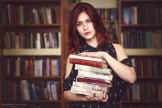 a woman holding a stack of books in her hands