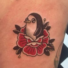 a penguin with a red bow around its neck on a woman's lower arm