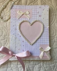 a card with pearls, bows and a heart in the middle on a quilted surface