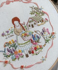 a close up of a embroidery on a piece of cloth with flowers in the background