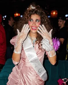 a woman in a pink dress and tiara holding her hands up to her face