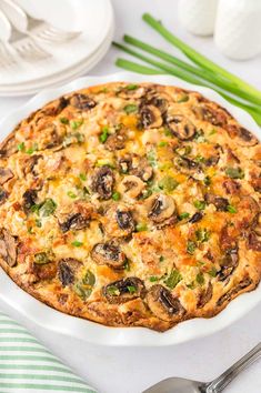 a white plate topped with a quiche covered in mushrooms