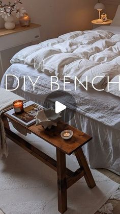 an unmade bed with white sheets and candles on the end table next to it