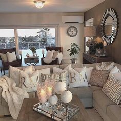 a living room filled with lots of furniture next to a large window covered in white pillows