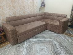 a brown sectional couch sitting on top of a marble floor next to a wall with mosaic tiles