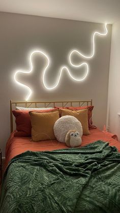 a teddy bear is sitting on the bed in front of a wall with neon lights