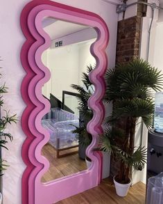 a mirror that is on the side of a wall next to a potted plant