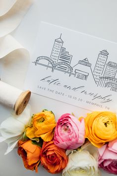 colorful flowers are laying on top of a white envelope with a cityscape in the background