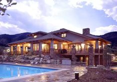 a house with a pool in front of it and mountains behind the house at night