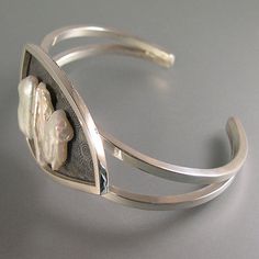 "This is a very contemporary, elegant bracelet made with 3 freshwater pearls measuring from 14mm to 20mm. It is fabricated by me from quite heavy, square, sterling silver wire. The swirls behind the pearls are etched. The etched area has been antiqued, or oxidized, to best show these beautiful pearls! This bracelet would best fit on a medium size wrist, but it is somewhat ajustable because of the open back. The top portion of this piece measures 1 3/4\" x 1 1/8\". All pearls are mounted with 2 p Modern Silver Pearl Bracelet With Oyster Design, Modern Silver Pearl Bracelet For Formal Occasions, Freshwater Pearl Bracelet, Sterling Silver Cuff Bracelet, Elegant Bracelet, Sterling Silver Cuff, Silver Cuff Bracelet, Silver Cuff, Silver Wire