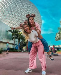 two people are posing for a photo in front of the spaceship dome at disney world