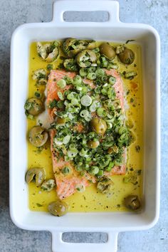 salmon with olives and capers in a white casserole dish that says oven roasted salmon