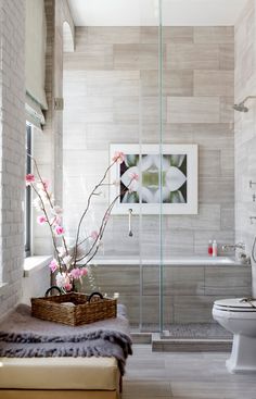 a bathroom with a tub, toilet and flower arrangement