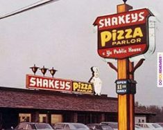 there is a restaurant called shakey's pizza parlor with cars parked in front