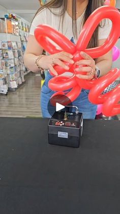 a woman is holding up some red balloons