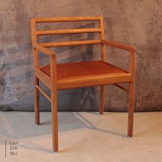 a wooden chair sitting on top of a floor next to a cement wall with a bike behind it