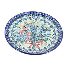 a blue and white bowl with flowers in it on a white background, there is a red bow at the bottom of the bowl