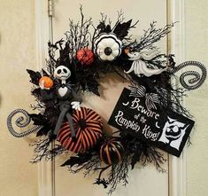 a wreath decorated with black and orange decorations on the front door to decorate for halloween