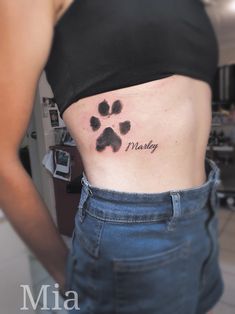 a woman with a dog paw tattoo on her stomach and the word marley written in cursive ink