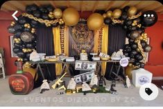 a party with balloons and decorations on the wall, including black and gold balloons hanging from the ceiling