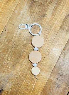 a wooden keychain with three circles attached to it on a wood table next to scissors