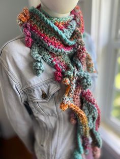 a mannequin wearing a multicolored crocheted scarf and denim jacket