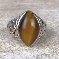 Tigers Eye Cabochon Ring Sz 7/Sterling Silver 925/Marquise Cut 16ct Solitaire/Heavy 9.2g/Designer Signed/Vintage Estate/Cross Hatch Design/Tigerseye Quartz Description Unique tigers eye ring in excellent vintage condition. 16ct of marquise cut tigers eye cabochon set in designer signed, stamped sterling silver setting. Face of ring measures 18mm from top to bottom and weighs a generous 9.2g. Interesting cross hatch design reminiscent of dragon scales. Out of the ordinary ring that would make a g Antique Brown Sterling Silver Jewelry, Brown Hallmarked Sterling Silver Jewelry, Vintage Brown Hallmarked Jewelry, Vintage Brown Jewelry With Polished Finish, Brown Sterling Silver Cabochon Ring, Brown Sterling Silver Ring With Cabochon, Vintage Brown Jewelry Stamped 925, Brown Hallmarked Vintage Ring, Vintage Brown Hallmarked Ring