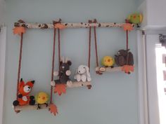 several stuffed animals are sitting on swings in the room, one is hanging from a tree branch