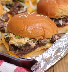 two cheeseburgers sitting on top of tin foil