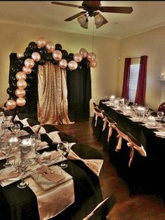 a dining room set up for a party with black table cloths and pink balloons