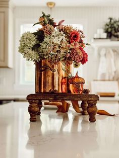 a vase filled with lots of flowers on top of a wooden table in a kitchen