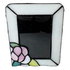 a small stained glass mirror with a flower on the front and bottom part, in white frame