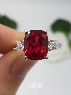 Made to order.  Please allow up to 3 weeks for the production of your selection. This listing is for a 925 non-plated sterling silver or non-plated gold three stone trellis ring with a high quality lab created ruby elongated cushion cut gemstone and high quality cubic zirconia diamond accent stones. Center Stone Gem Type: Lab Created Ruby Shape: Elongated Cushion Cut Size: 10x8mm Weight: 3.5 carats approximately Quality: AAA Hardness: 9 Mohs Accent Stones Gem Type: Lab Created Cubic Zirconia Diamonds Shape: Round Brilliant Size: (2) 3.5mm Color: White Quality: 6A Hardness: 8.5 Mohs Available in the following Metal Options (all metal are non-plated and solid) 925 Sterling Silver 10kt White Gold (non-rhodium plated) 10kt Yellow Gold 14kt White Gold (non-rhodium plated) 14kt Yellow Gold 14kt Formal Sterling Silver Jewelry With Rectangular Stone, Sterling Silver Jewelry With Rectangular Prong Setting, Sterling Silver Jewelry With Rectangular Stone And Prong Setting, Sterling Silver Jewelry With Rectangular Stone In Prong Setting, Sterling Silver Ring With Rectangular Stone For Formal Events, Formal Sterling Silver Ring With Rectangular Stone, Sterling Silver Rings With Rectangular Stone For Formal Events, Sterling Silver Rings With Rectangular Stone For Formal Occasions, Elegant Ruby Ring With Rectangular Polished Finish