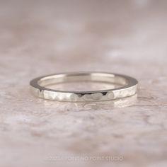 a white gold wedding band with dots on it sitting on top of a marble surface