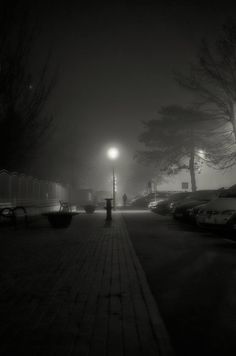 a dark street with cars parked on it