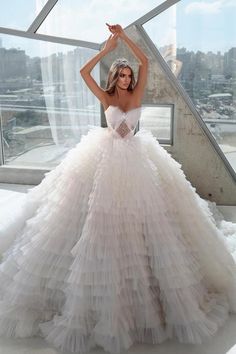 a woman in a wedding dress posing for the camera with her hands behind her head