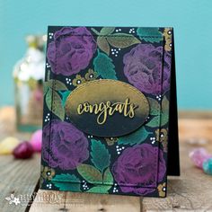 a close up of a card on a wooden table with flowers and the words congrats written in cursive writing